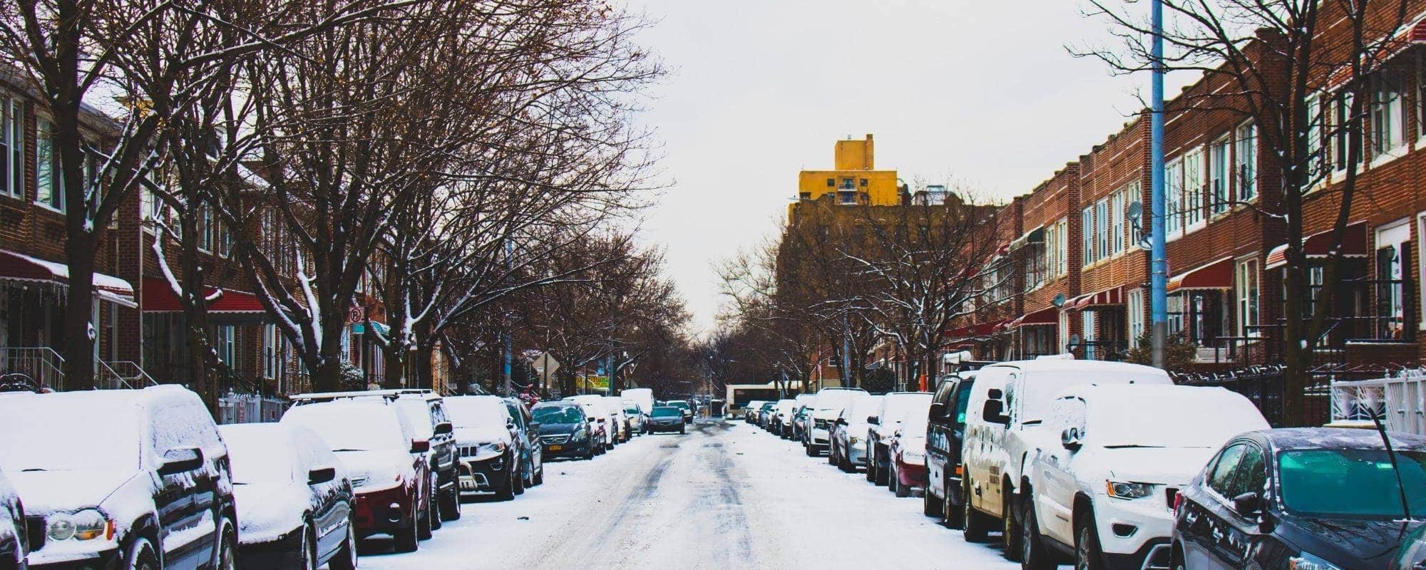 Residential area-Cars parked on both sides of road-Snow on road and cars